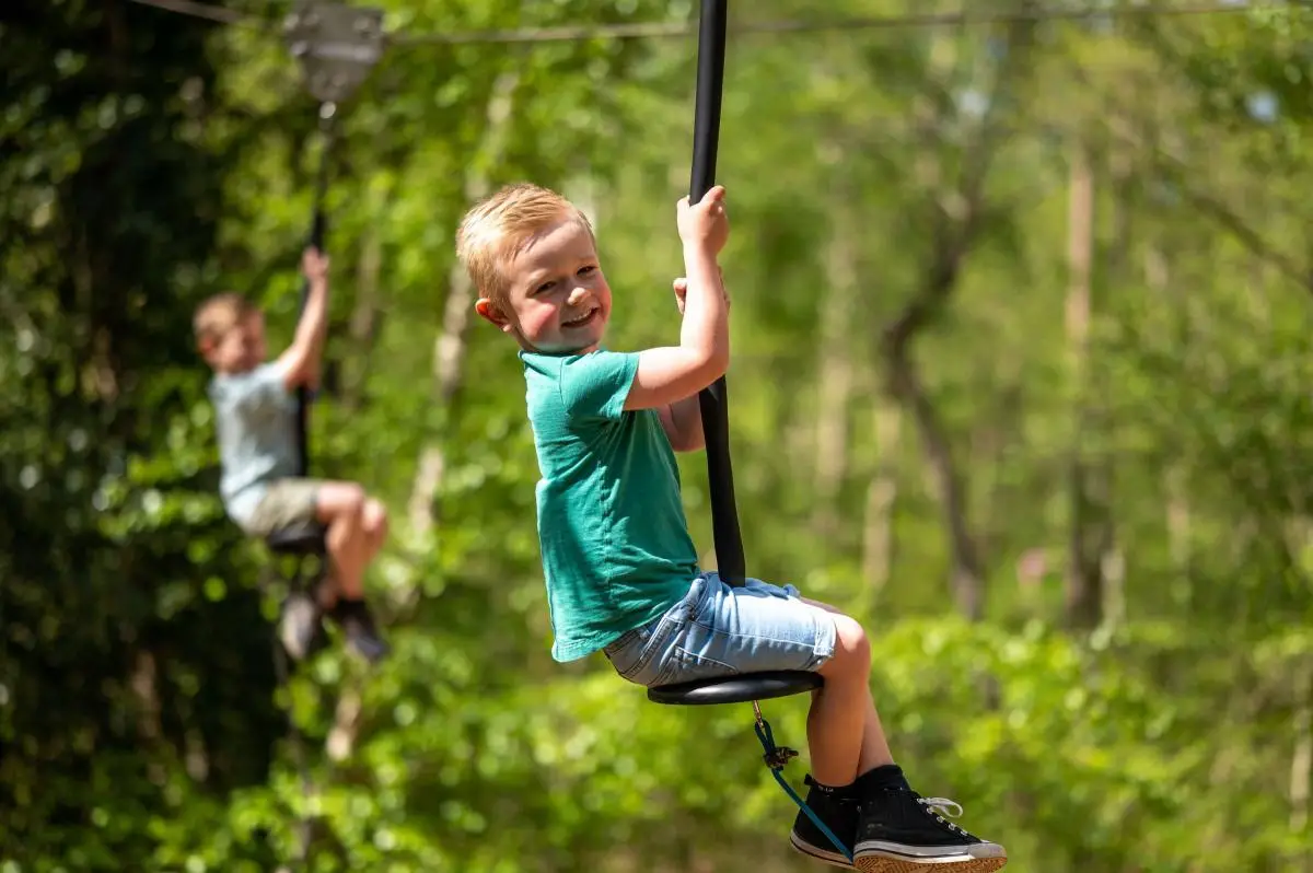 two children on swings at bewilderwood in norfolk