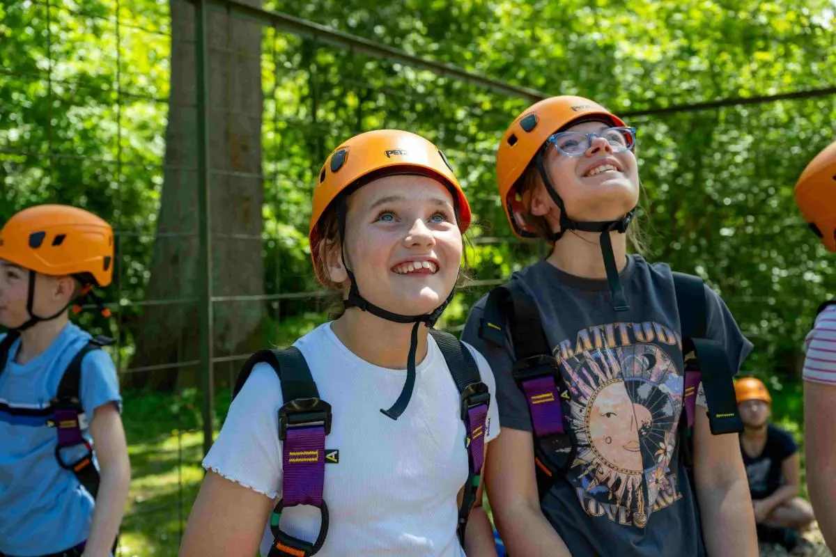 children in hard hats and safety harnesses on an adventure activity